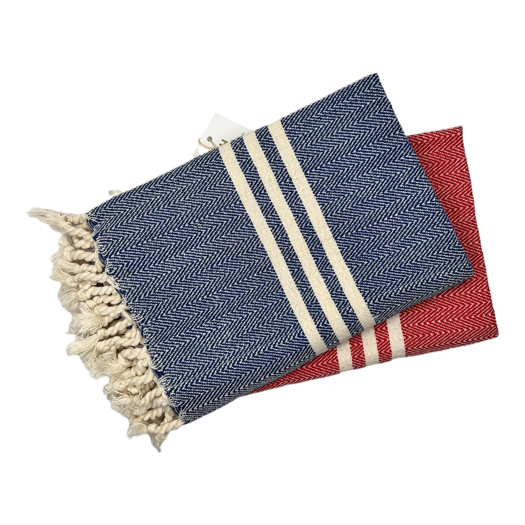 Two Sultan Hand Towels from turkanhome.com—one blue, one red with white stripes and fringed edges—are stacked together against a white background.