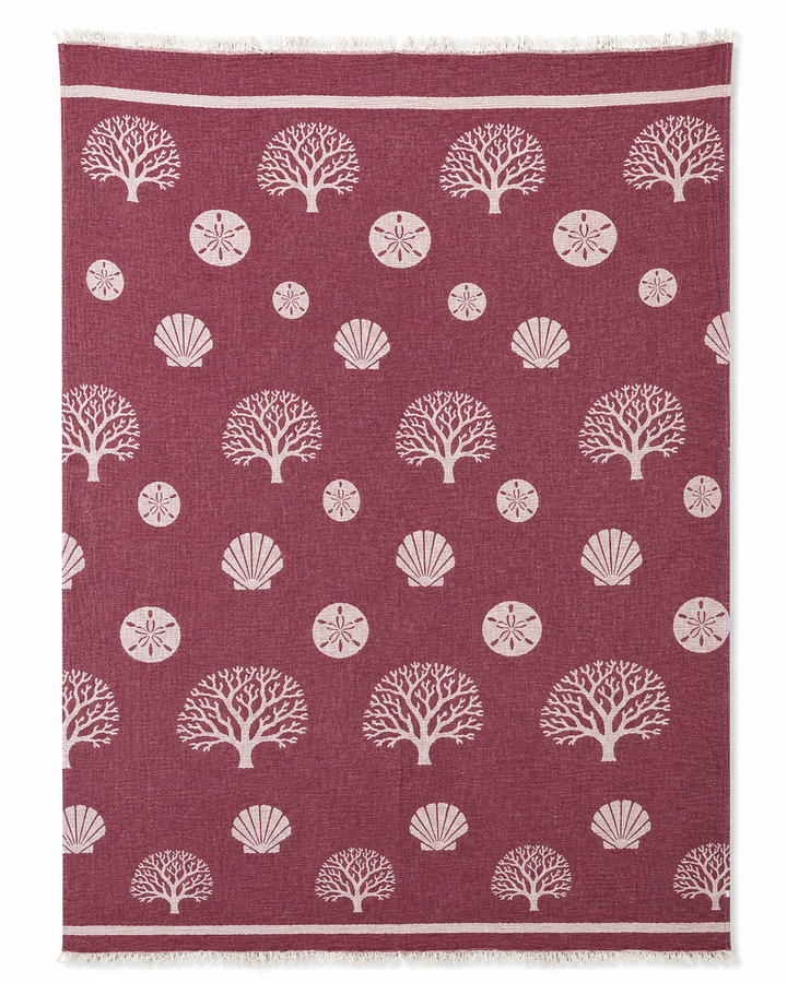 A maroon rug featuring a pattern of white coral, sand dollars, and seashells spaced evenly across its surface brings coastal charm to any room—perfectly complementing the Coastal Muslin Throw Blanket – Reversible Turkish Cotton from turkanhome.com.