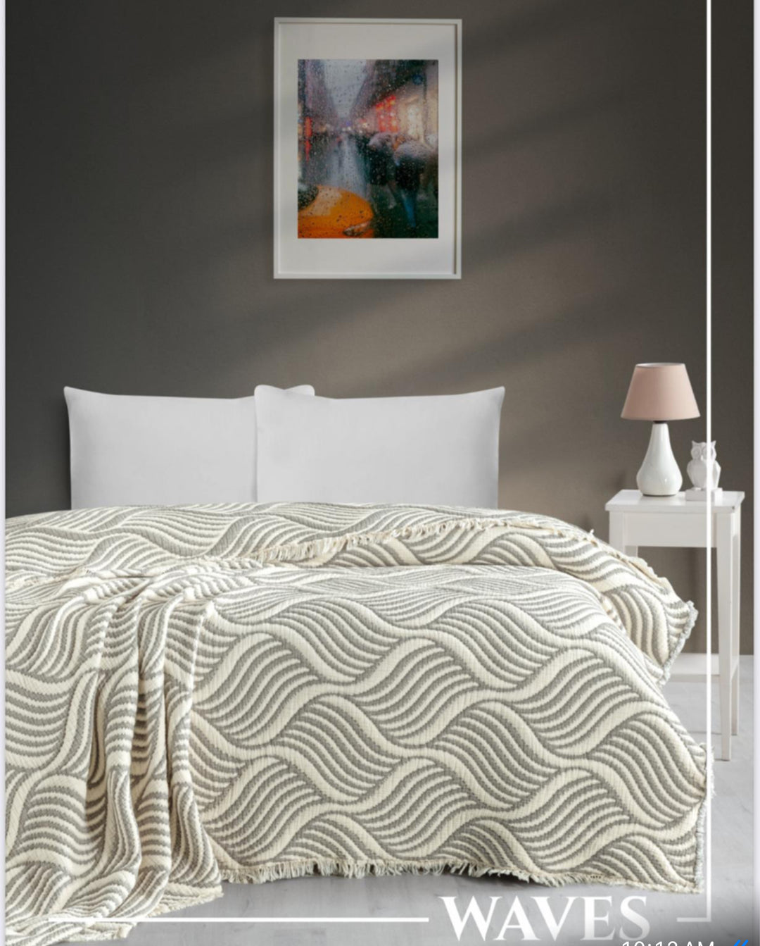 A neatly made bed with a wavy beige blanket, white pillows, and a nightstand sets the scene for cozy homes—perfect inspiration for holiday gifting with "Give a Gift of Comfort" from turkanhome.com.