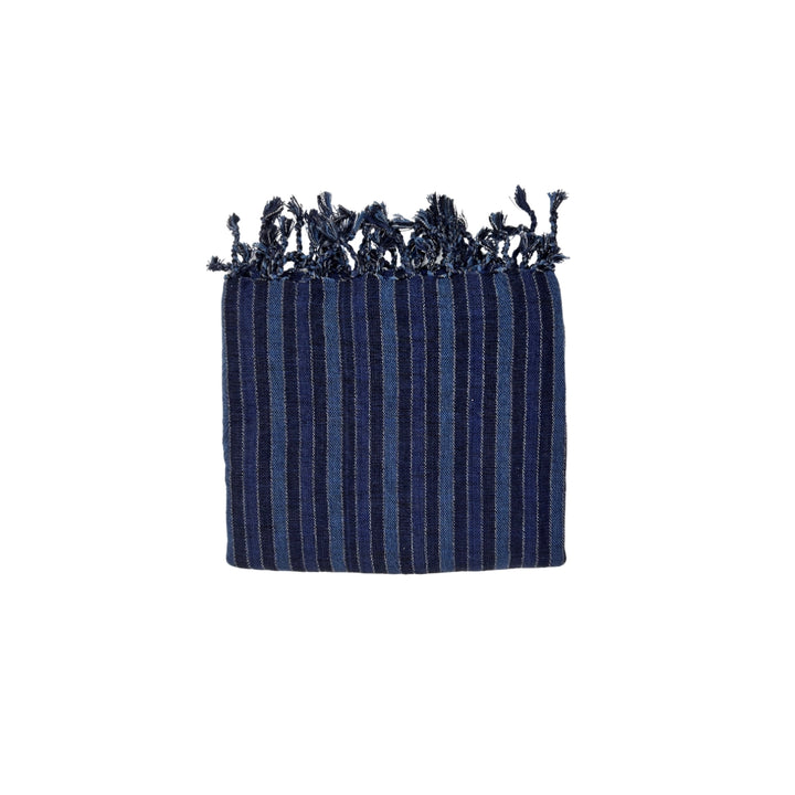 The Black Sea Handwoven Turkish Towel from turkanhome.com is crafted from all-natural fibers and features navy blue stripes, light blue vertical lines, and fringed edges. It can be used as a towel, throw, or shawl.