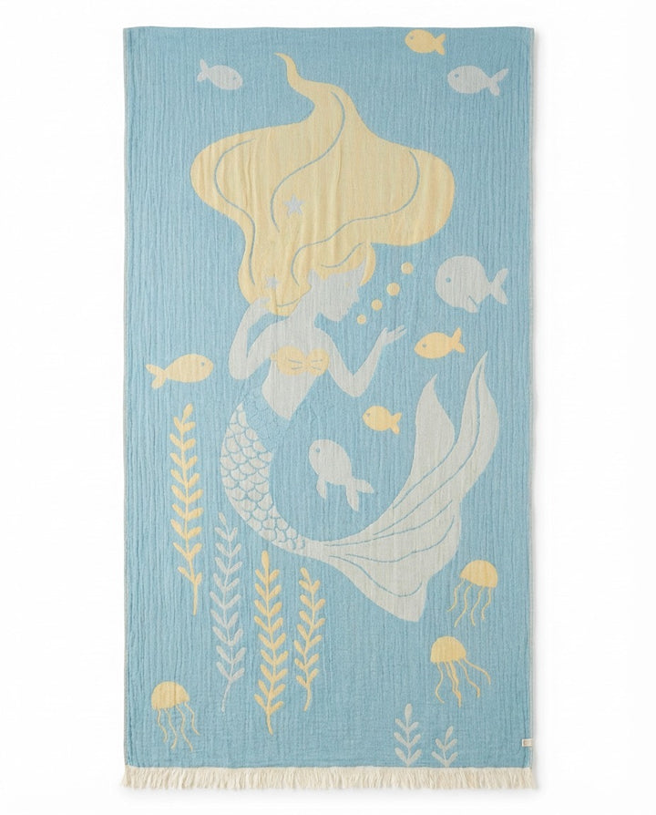 The Mermaid Turkish Towel by turkanhome.com is a light blue, 100% cotton towel with a blonde mermaid, yellow fish, seaweed, bubbles, and jellyfish design. It features cream fringe and quick-drying comfort—perfect for the beach!.