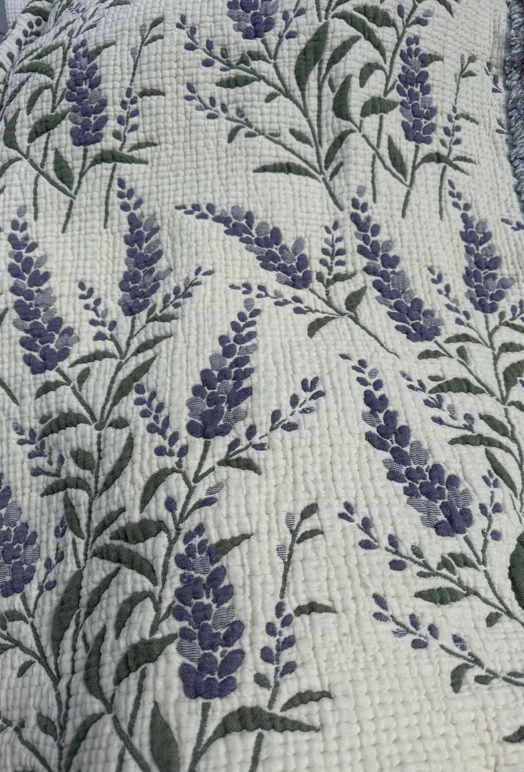 Introducing the 7-Layer Cotton Muslin Quilted Blanket - Lavender Field from turkanhome.com, an all-season bedspread crafted from soft cotton muslin and adorned with a quilted pattern of delicate purple lavender flowers and green stems on a cream background for lasting comfort.