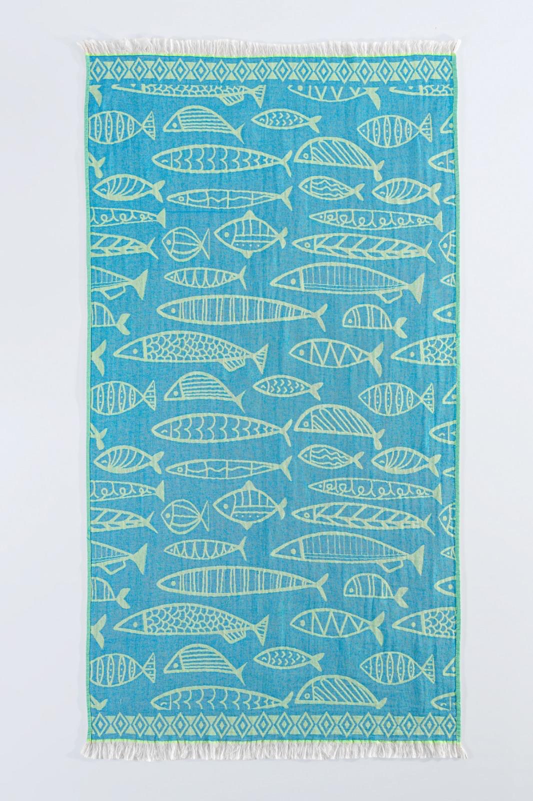 The Fishes Turkish Towel by turkanhome.com is a blue, rectangular 100% cotton jacquard towel with white geometric fish patterns, a diamond border, and fringed short edges.