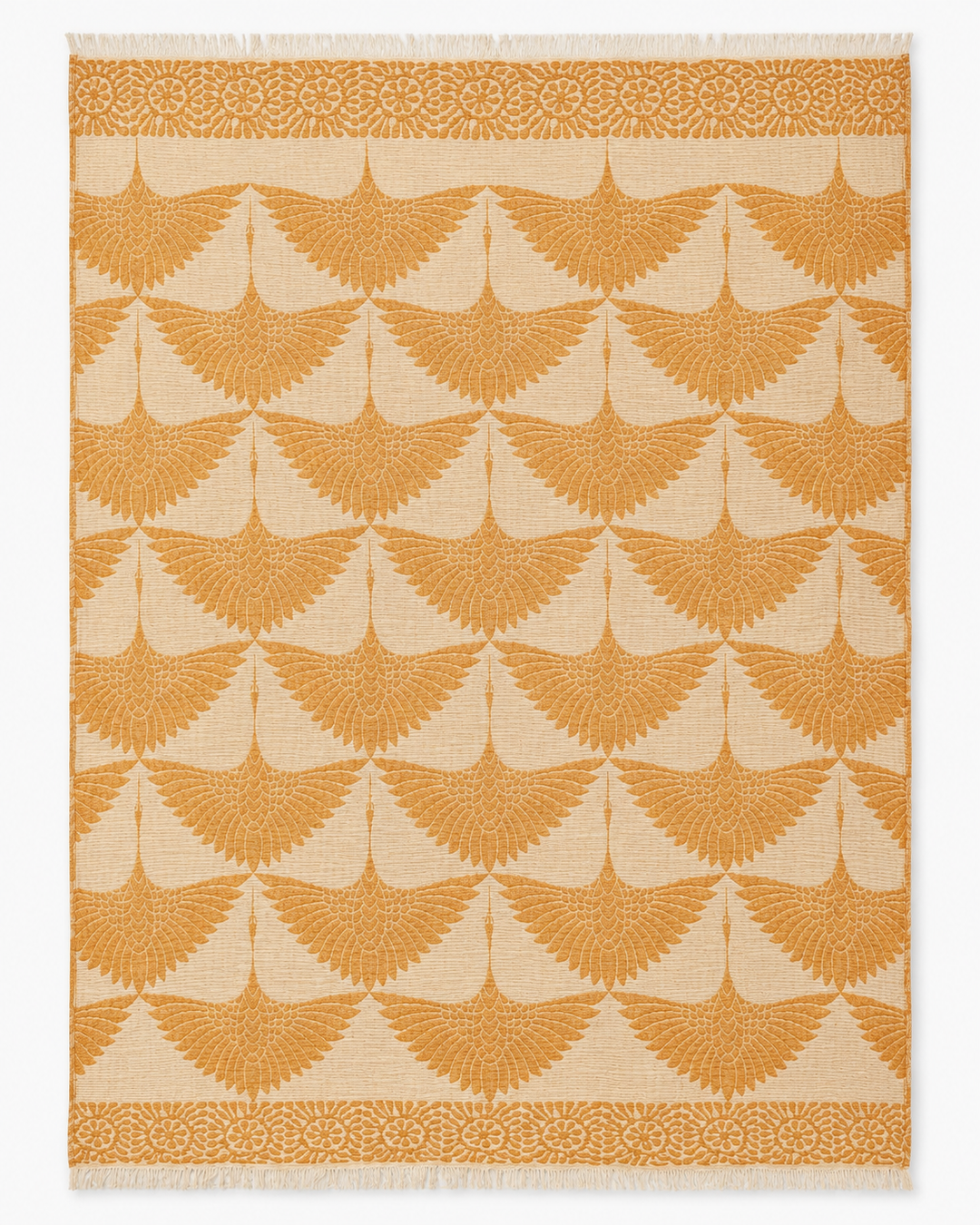 A beige Crane Muslin Throw Blanket from turkanhome.com, featuring a reversible design with a natural border and adorned with symmetrical, orange fan-shaped motifs and an orange floral accent along the top and bottom edges, echoing intricate Turkish-inspired patterns.