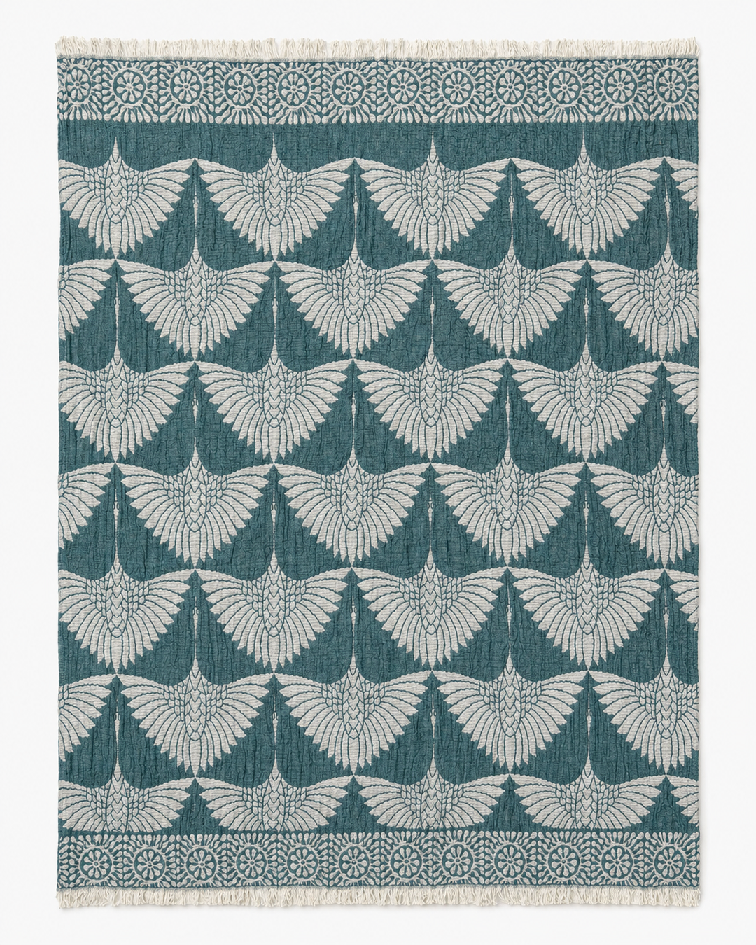 The Crane Muslin Throw Blanket from turkanhome.com features a reversible design with a repeating pattern of stylized crane wings in white on a teal background, accented by a natural decorative border and short fringe on two edges. Crafted from Turkish cotton, this throw offers both style and comfort for your home.