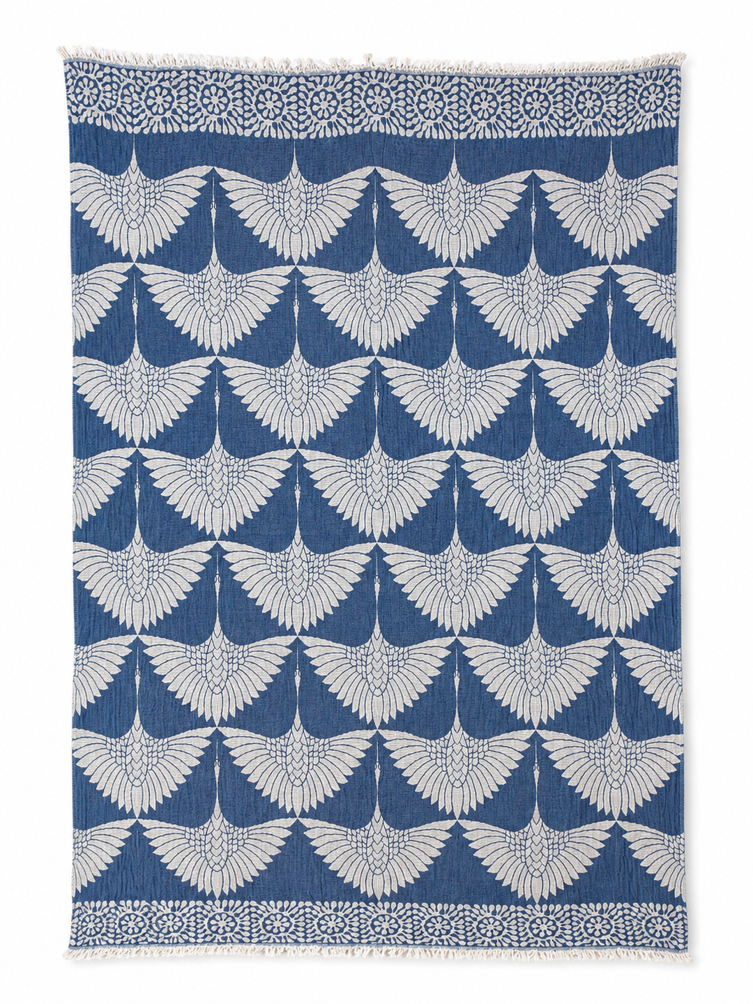 The Crane Muslin Throw Blanket Natural Border by turkanhome.com features a bold, reversible design with a striking blue base and a repeating white crane motif, each bird depicted with outstretched wings. Crafted from premium Turkish muslin cotton, this throw is accented by a perfectly symmetrical geometric floral border for added elegance.