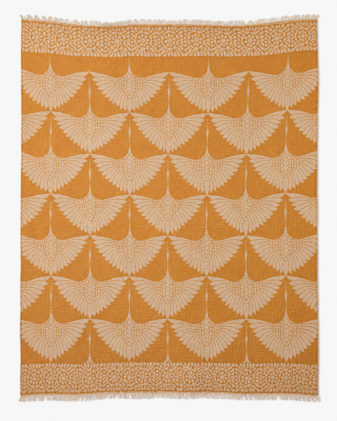 Introducing the Crane Muslin Throw Blanket Natural Border–Reversible Turkish Cotton by turkanhome.com: a square throw blanket crafted from premium Turkish cotton, featuring a repeating pattern of cream-colored, stylized cranes with outstretched wings set against a rich mustard yellow background. Accented with an elegant natural-hued geometric border, this reversible blanket effortlessly adds both sophistication and comfort to your living space.