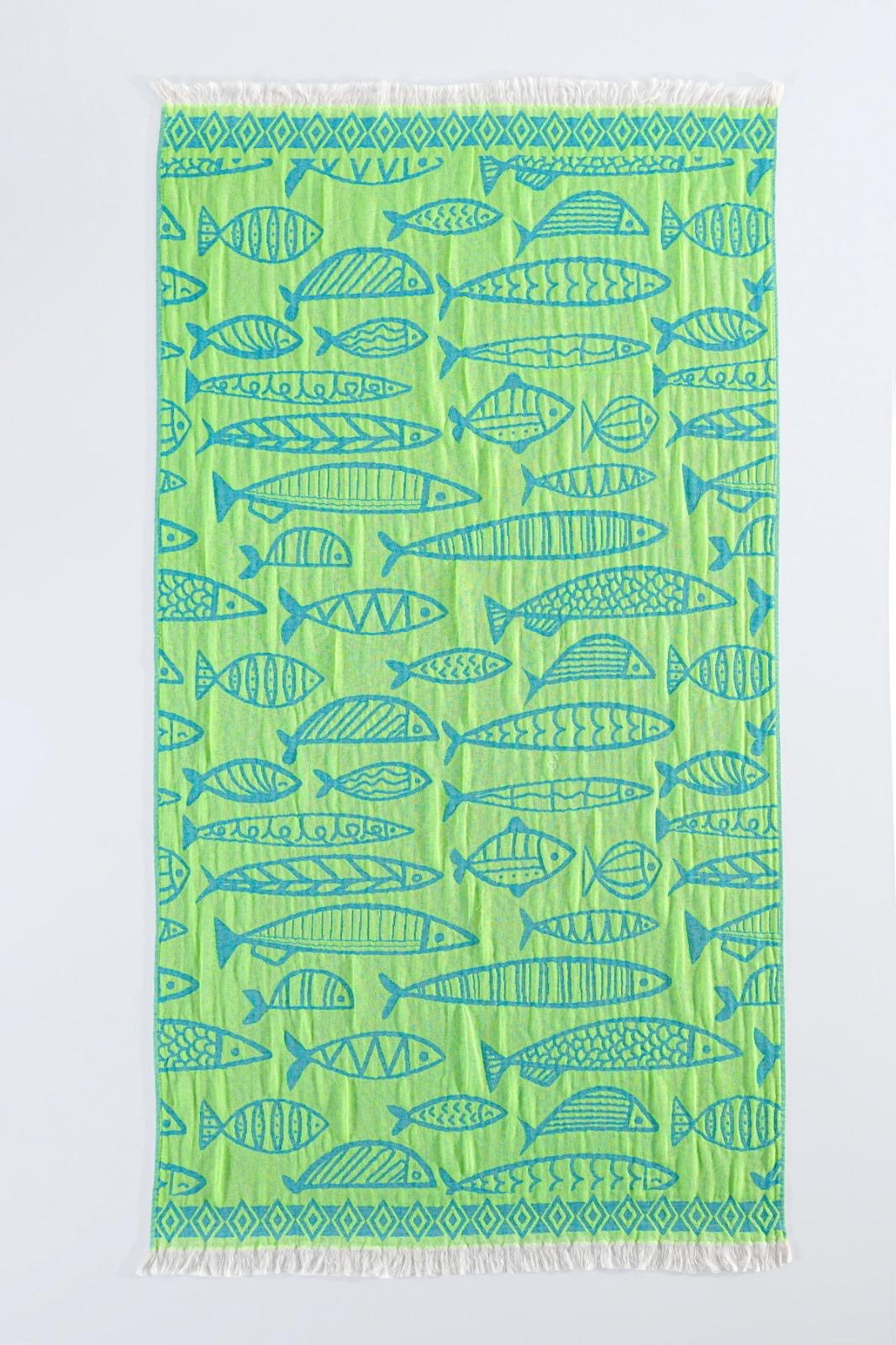 The Fishes Turkish Towel by turkanhome.com is a green rectangular jacquard-woven 100% cotton towel with blue fish and geometric patterns, plus white fringe on the short edges for a soft, durable finish.
