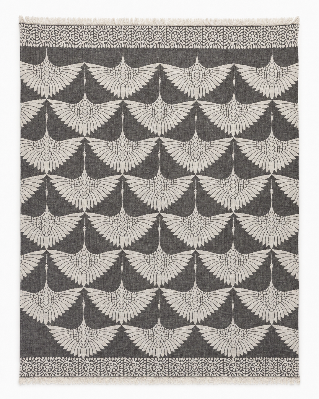 Experience the refined elegance of turkanhome.com's Crane Muslin Throw Blanket Natural Border–Reversible Turkish Cotton, featuring a sophisticated square design with a soft gray backdrop and a repeating white geometric pattern inspired by classic crane motifs, reminiscent of outstretched bird wings. Its border is adorned with circular floral accents, echoing the luxurious detail found in traditional Turkish cotton blankets.