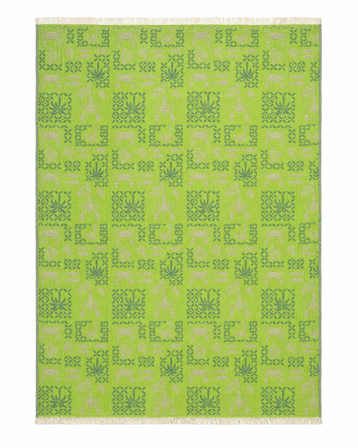 A rectangular Sea Life Muslin Throw Blanket by turkanhome.com, crafted from reversible Turkish cotton, features a symmetrical pattern of darker green leaf and square motifs on a green background with light fringe along the shorter edges. The design repeats evenly across the surface, making it a perfect addition to coastal home décor.