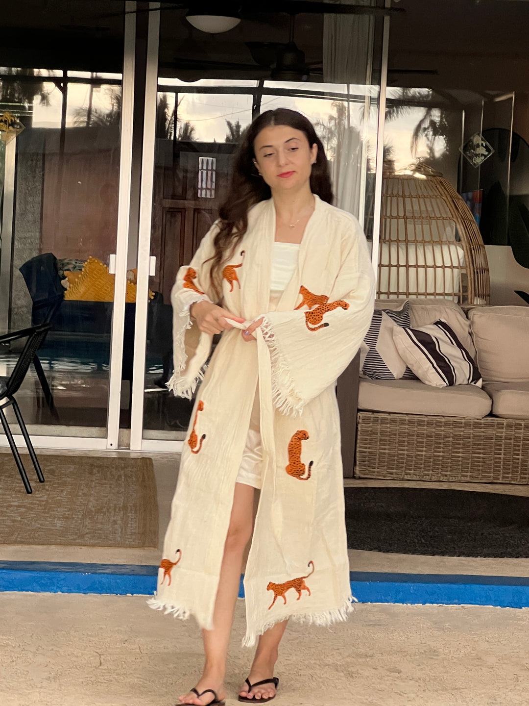 Woman wearing a natural color kimono robe with orange leopard patterns in a living room setting