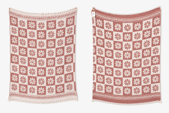 Two Daisy Muslin Throw Blankets by turkanhome.com, both featuring a repeating white flower pattern on pink, decorative borders, and fringed edges, are displayed side by side against a white background.