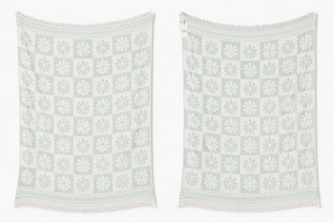 The Daisy Muslin Throw Blanket from turkanhome.com comes in light green and white with a floral and geometric pattern plus fringe on both ends. Displayed side by side, these Turkish cotton throws add charm to any cottage-inspired space.