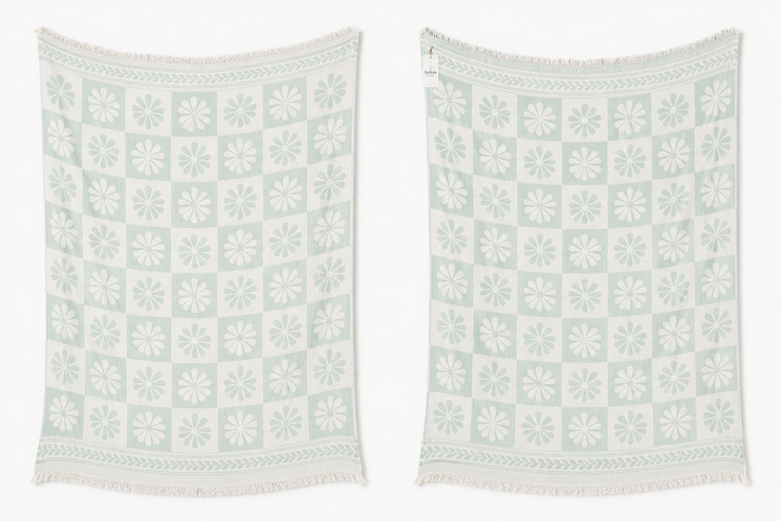 The Daisy Muslin Throw Blanket from turkanhome.com comes in light green and white with a floral and geometric pattern plus fringe on both ends. Displayed side by side, these Turkish cotton throws add charm to any cottage-inspired space.