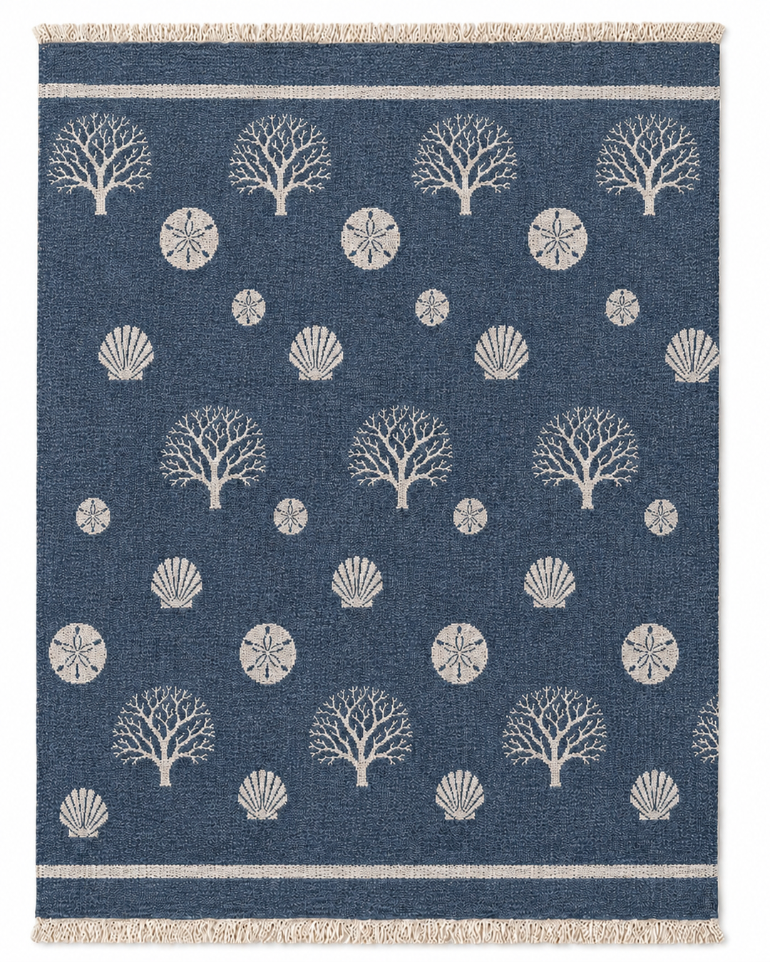 Bring seaside charm to any room with the Coastal Muslin Throw Blanket – Reversible Turkish Cotton from turkanhome.com, featuring a blue background adorned with white tree, shell, and sand dollar patterns arranged in neat rows, bordered by double white stripes and finished with fringe at the edges.
