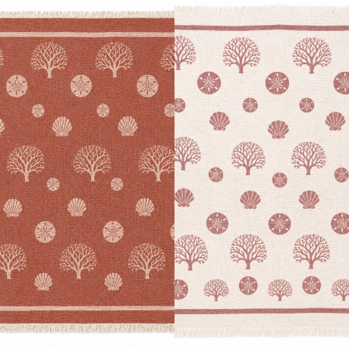 Two woven textiles from turkanhome.com are shown side by side: on the left, the Coastal Muslin Throw Blanket – Reversible Turkish Cotton appears in a rust hue, adorned with tan shells, sand dollars, and coral motifs; on the right, the same blanket is displayed in beige with rust-colored sea life patterns. Both sides feature soft Turkish muslin cotton and fringed edges, making this cozy, reversible coastal throw perfect for seaside retreats.