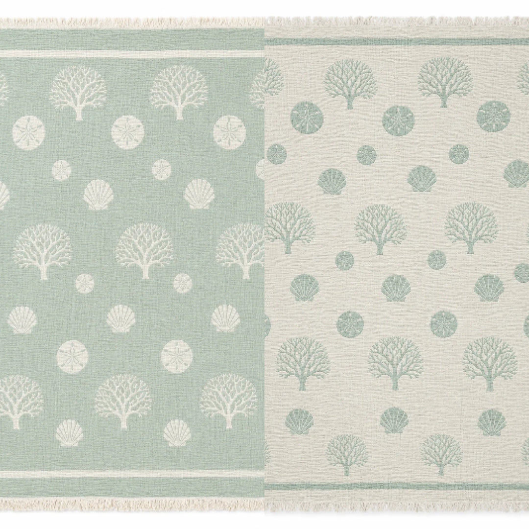 A woven rug featuring a tree and circle pattern divided vertically, with the left side in green accented by white designs and the right side in white with matching green motifs. Each half mirrors the other in reversed colors, capturing the chic contrasts reminiscent of turkanhome.com’s Coastal Muslin Throw Blanket – Reversible Turkish Cotton.
