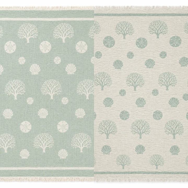 A woven rug featuring a tree and circle pattern divided vertically, with the left side in green accented by white designs and the right side in white with matching green motifs. Each half mirrors the other in reversed colors, capturing the chic contrasts reminiscent of turkanhome.com’s Coastal Muslin Throw Blanket – Reversible Turkish Cotton.