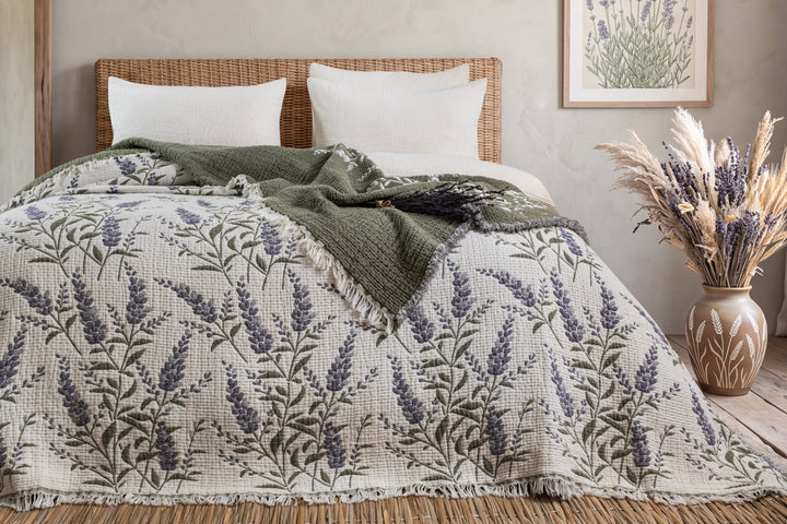 7-Layer Cotton Muslin Quilted Blanket Lavander with a lavender floral print layered with a solid olive-green throw on a bed.