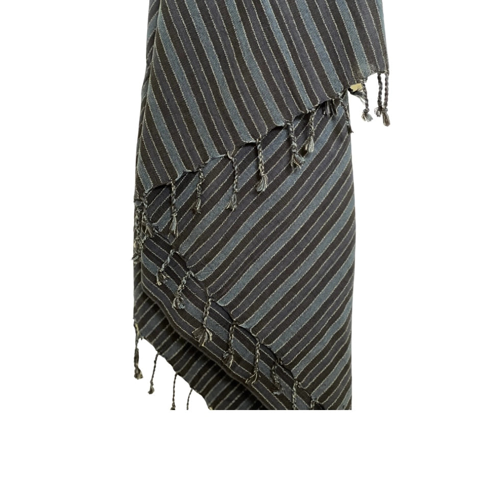 A close-up of the Black Sea Handwoven Turkish Towel by turkanhome.com shows its diagonal dark and light lines, fringe edges, and tassels. Crafted from all-natural fibers, the towel is set against a plain white background.