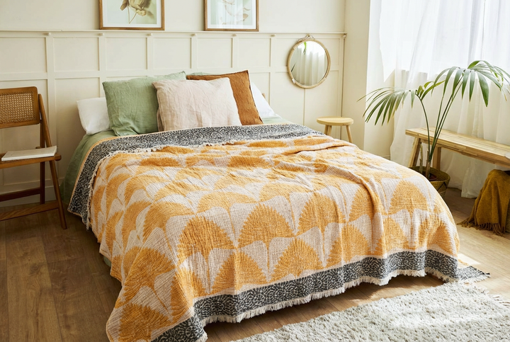 Create a cozy haven with Give a Gift of Comfort from turkanhome.com—a sunlit bedroom set featuring green and white pillows, a mustard brown cushion, and a patterned quilt. Perfect for home inspiration or as a thoughtful Christmas gift.
