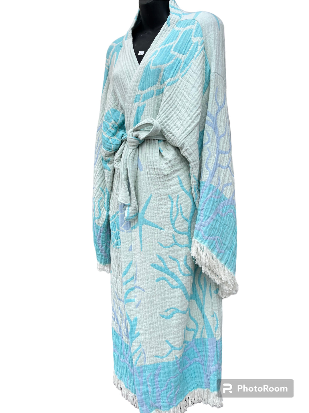 The Blue Turtle Robe by turkanhome.com is a light blue and white kimono with a sea-inspired pattern, sash belt, wide sleeves, and fringe trim—ideal as elegant beach or lounge wear. Displayed on a black mannequin against a white background.